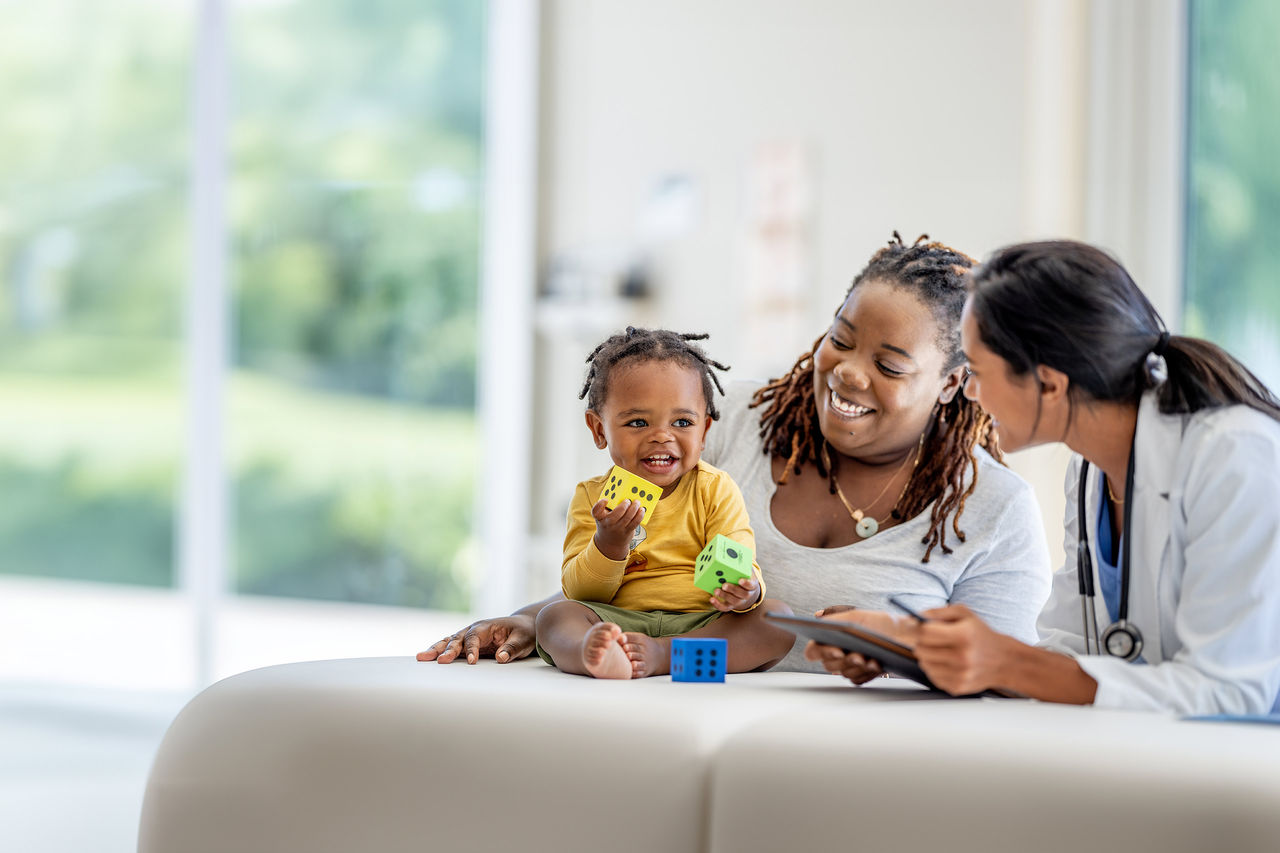 Mom and infant boy smiling as they have a conversation with their provider.