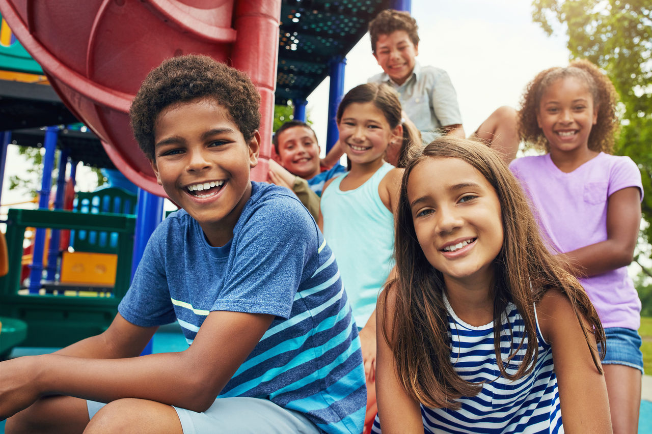 A group of kids smiling together on a playground.