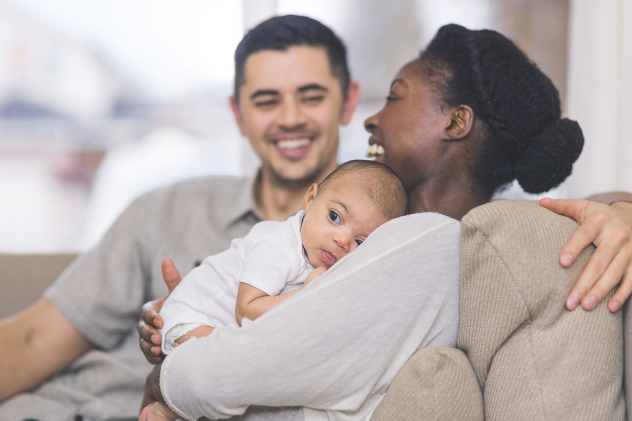 Mother and father on the couch with baby.